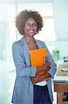 Portrait of smiling office worker holding orange file and smartphone