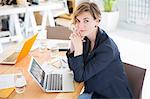 Portrait of woman sitting at desk with laptop in office