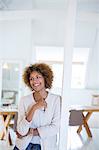 Portrait of woman leaning on column in office and smiling