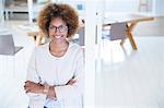 Portrait of woman leaning on column in office and smiling