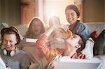 Group of teenagers eating pizza on sofa in living room