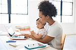 Mother working from home with daughter sitting on her lap