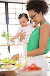 Woman with baby girl preparing meal in domestic kitchen