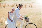 Young couple riding bike in meadow