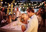 Young couple kissing during wedding reception in domestic garden