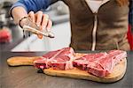 Young Woman salting a raw steak, Munich, Bavaria, Germany