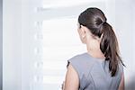 Rear view of a businesswoman looking out office window, Munich, Bavaria, Germany