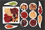Healthy dried fruit selection in white porcelain bowls over slate background.