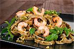 Luxurious seafood pasta on black plate with fresh arugula.