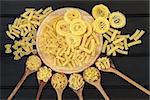 Italian dried food selection on a wooden board and in olive wood spoons over dark wood background.