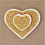 Kamut khorasan wheat in heart shaped dishes over hessian background.