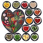 Spice and herb collection on heart shaped slate and rounds and in porcelain bowls over white background.