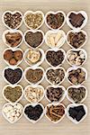 Large chinese herbal medicine selection in heart shaped bowls over bamboo background.