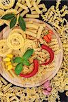 Italian food ingredients with pasta, herb and spice selection on a wooden board.