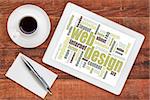 web design word cloud on a digital  tablet with a cup of coffee on a rustic wooden table