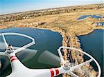 rotating propellers of an airborne quadcopter drone flying over lake and swamp landscape in northern Colorado, early spring