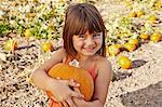 Portrait of girl holding pumpkin in pumpkin field