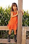 Portrait of girl standing and holding onto field fence