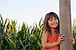 Portrait of girl holding onto field fencepost