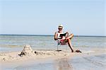 Mature man reading book on beach