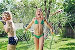 Girl and boy playing with water in garden