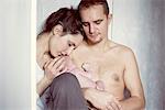 New parents sitting with newborn baby
