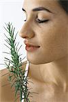 Young woman smelling spring of fresh rosemary, eyes closed