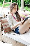 Young woman reading on sofa outdoors