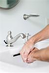 Man washing hands in bathroom sink