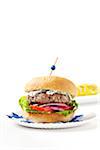 Greek style burger with spiced corn on the cob in the background, studio shot on white background