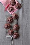 Chocolate, coconut macaroon cookies on a cooling rack with a pink, cloth napkin and twine, studio shot on a grey background