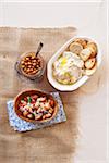 Three bean side dishes, kidney beans, hummus and chick peas in bowls on burlap, studio shot