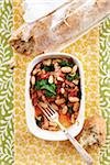 Sausage, bean and kale stew with fork in a bowl and crusty bread, studio shot