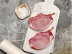 Raw Pork Chops on White Cutting Board on Marble, Studio Shot