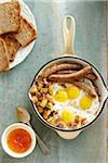 Overhead View of Skillet with Sunny Side up Eggs, Sausage, and Hashbrowns served with Whole Wheat Toast and Apricot Jam on Wooden Background