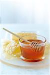 Close-up of Small Glass Bowl with Raw Honey and Honey Dipper and Honey Combs on Tabletop
