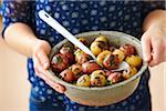 Close-up of Woman's Hands Holding Bowl of Grilled Red and White Baby Potatoes