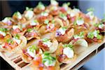 Close-up of appetizers with onions, cheese, tomatoes and sour cream on a potato chip on a board, at an event, Canada