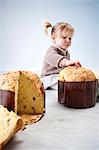 Female toddler sitting on floor with fingers on pannetone cake