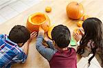 Siblings carving pumpkin in dining room