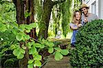 Young couple in garden pruning bush