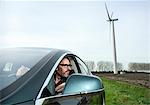 Man in car with wind turbine in background