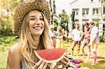 Woman wearing straw hat eating watermelon