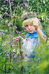 Boy dressed up and playing with plants in garden