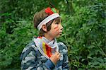 Boy dressed up in face paint and playing in forest