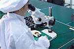 Worker using microscope in factory that specialises in creating functional circuits on flexible surfaces