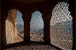 Looking through stone lattice window to the walls of Amber Fort; Amer, Jaipur, India