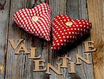 Cardboard Word Valentine and Two Handmade Textile Red Polka Dot Hearts closeup on Rustic Wooden background
