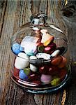 Sweet Colored Gum and Hard Candies in Glass Jar with Lid closeup on Rustic Wooden background