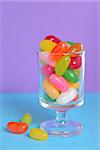 color Jelly Beans in glass on lila background